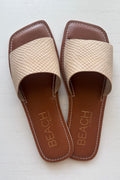 Pair of beige sandals with brown soles on a white background