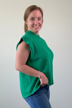 Woman wearing a green sleeveless top and blue jeans against a plain background