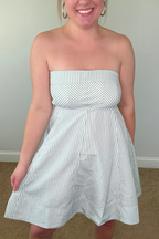 Woman wearing a strapless white and blue striped dress against a plain background