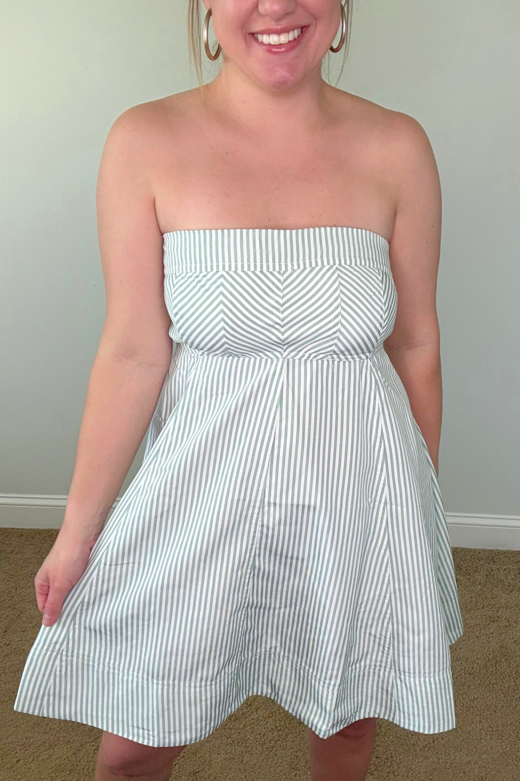 Woman wearing a strapless white and blue striped dress against a plain background