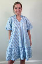 Woman wearing a blue and white striped dress against a plain background