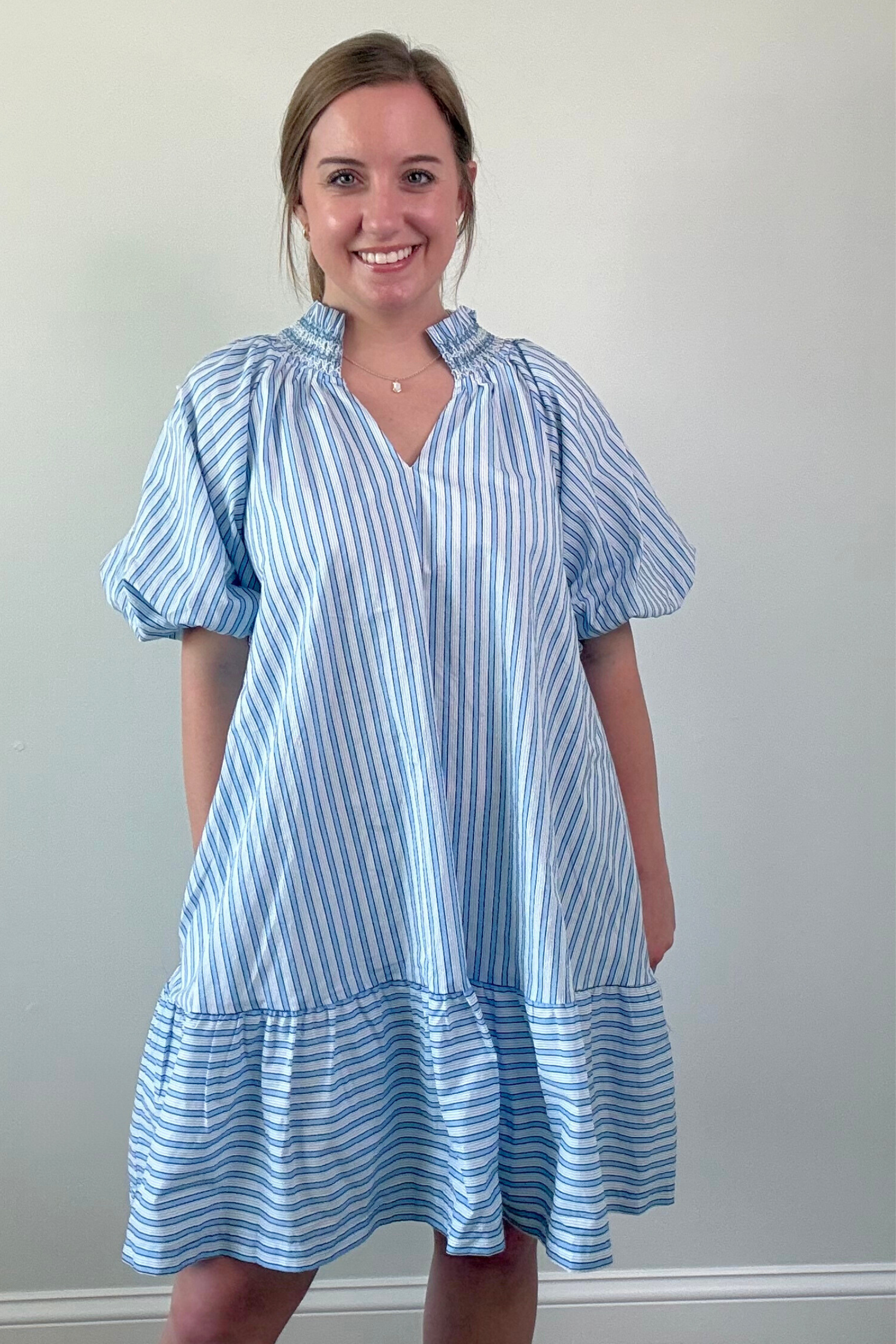 Woman wearing a blue and white striped dress against a plain background