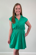 Woman wearing a green dress standing against a plain background