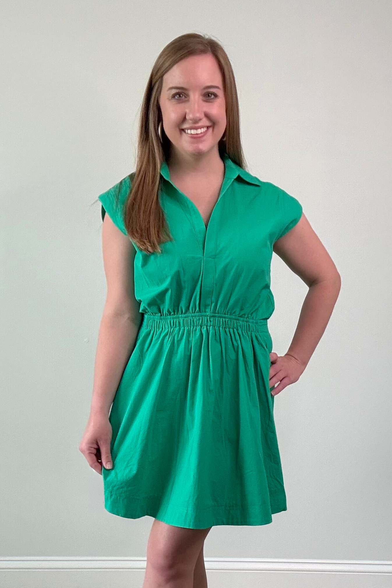 Woman wearing a green dress standing against a plain background