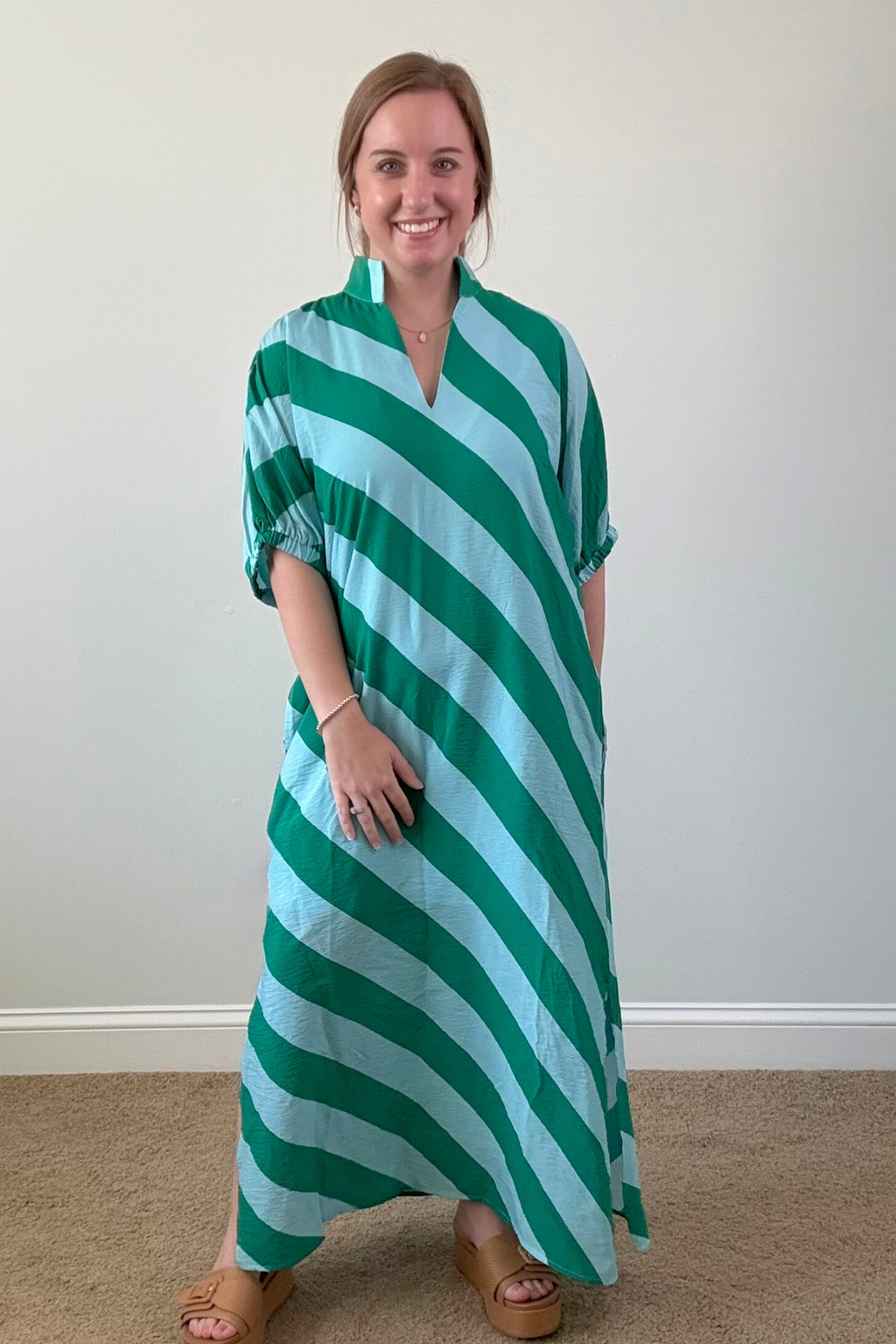 Woman wearing a green and white striped dress against a plain background