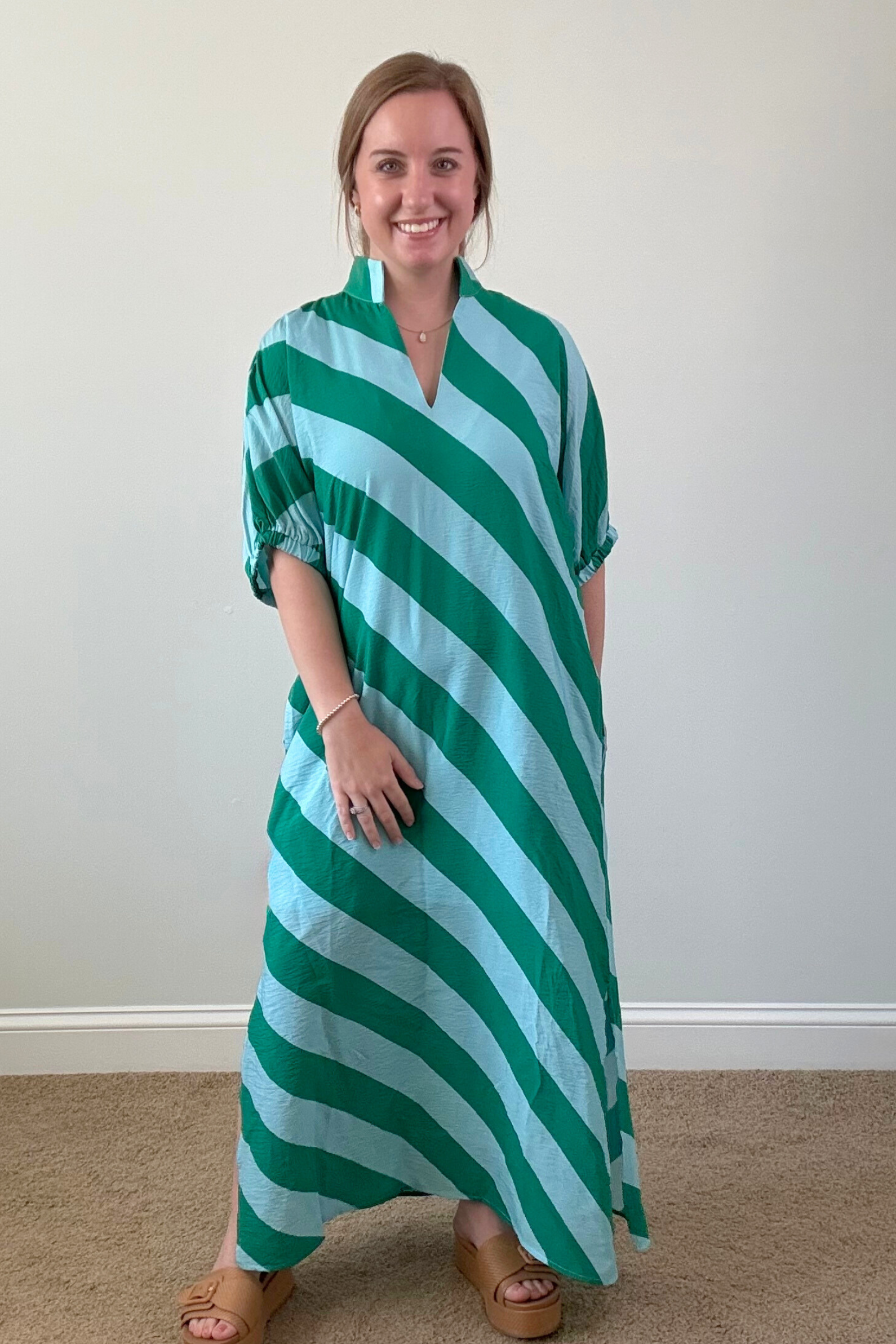 Woman wearing a green and white striped dress against a plain background