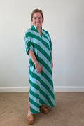Woman wearing a green and white striped dress against a plain background