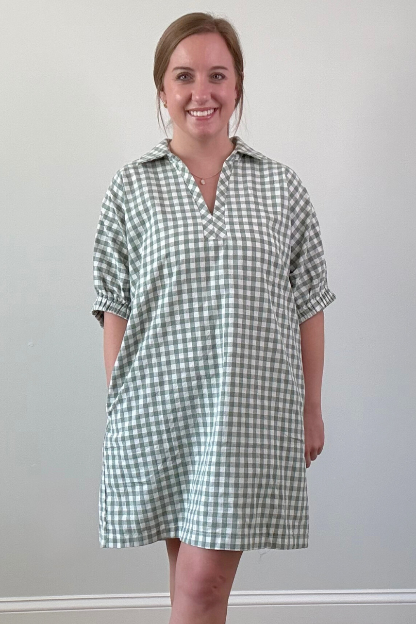 Woman wearing a green and white checkered dress against a plain background