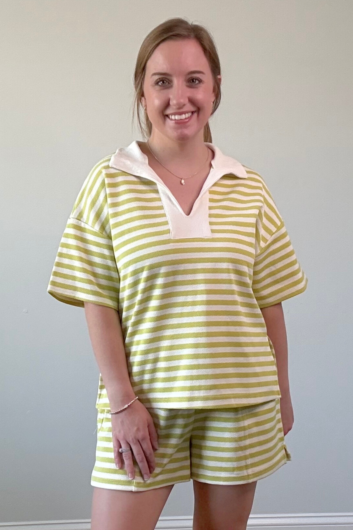 Woman wearing a yellow and white striped outfit against a plain wall.