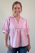 Woman wearing a red and white striped blouse against a plain background