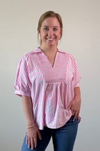 Woman wearing a pink and white striped blouse against a plain background