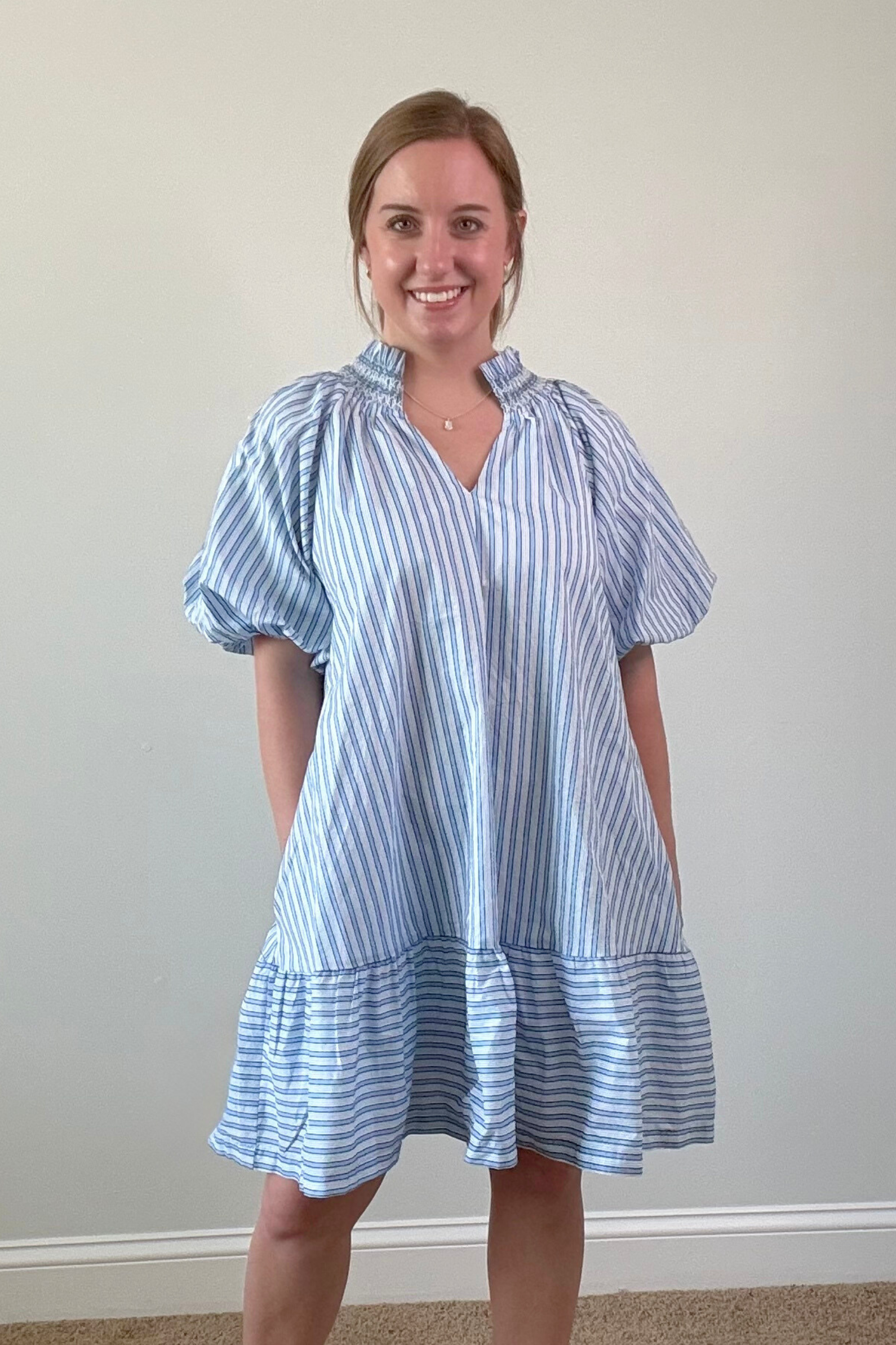 Woman wearing a blue and white striped dress against a plain background