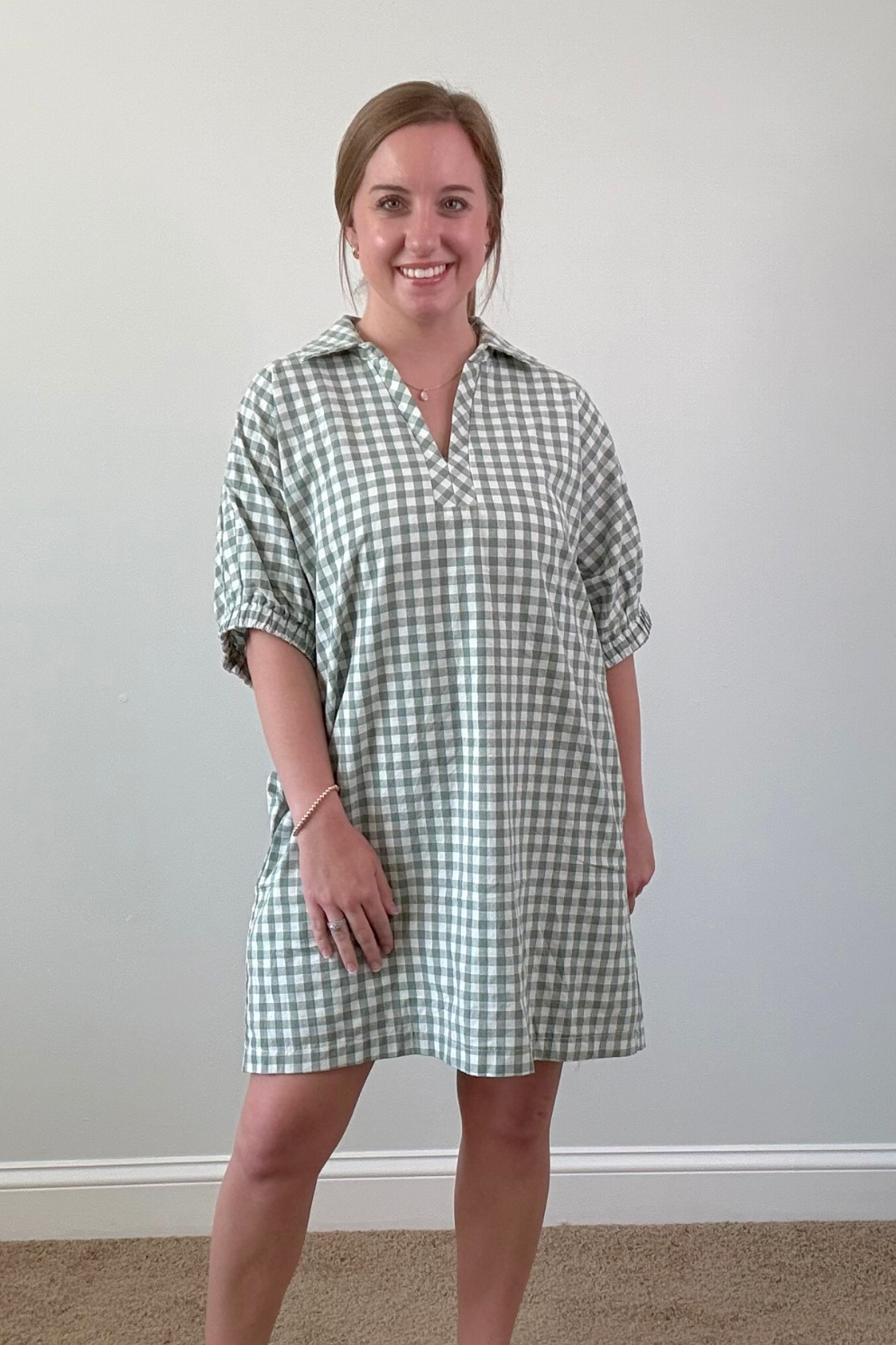 Woman wearing a green and white checkered dress against a plain background